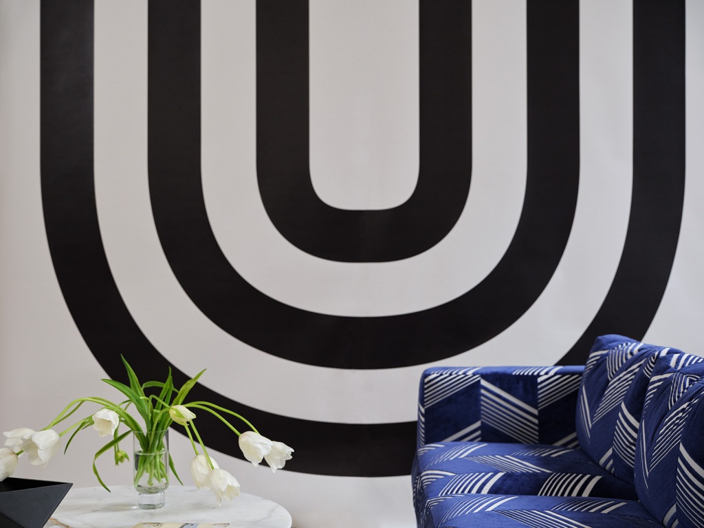 "Virginia" paneles de revestimiento de paredes en blanco y negro y un sofá cubierto con líneas geométricas en azul marino y blanco de la "Jessy" Terciopelo cortado de Cul-de-Sac por Victor Glemaud.